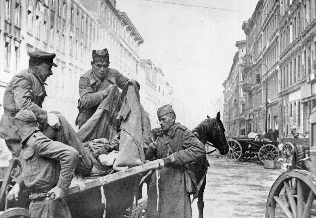 Soviet orderlies shift from a stretcher to a wagon of a wounded soldier