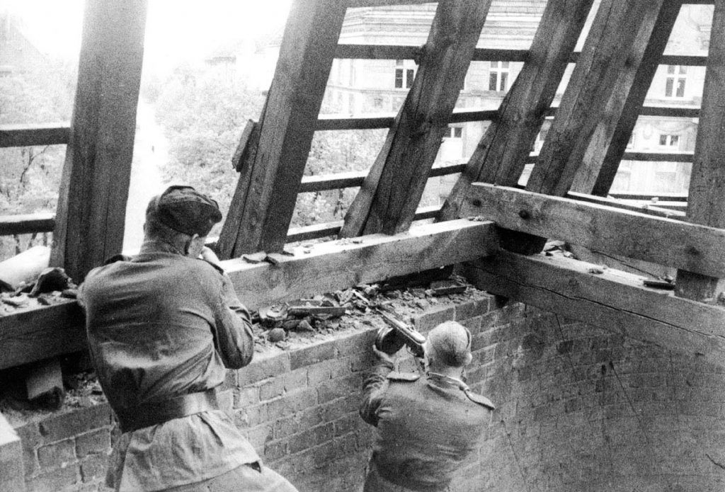 Soviet troops take up position in the roof of a building to advance through the city streets