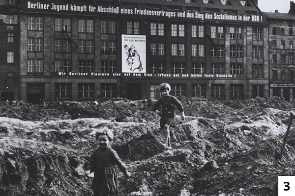 Children play in the Soviet-controlled section of Berlin circa 1958. The signs in the background include slogans promoting socialism and an East German youth group called Berlin Pioneers. From the CIA booklet "A City Torn Apart: Building of the Berlin Wall."/Public Domain
