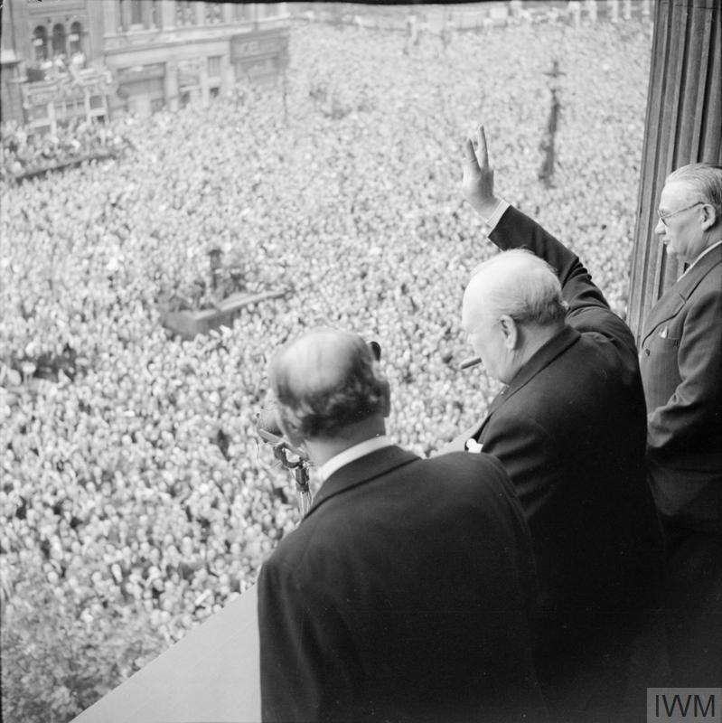 Churchill waves to crowds in Whitehall on the day he broadcast to the nation that the war with Germany had been won