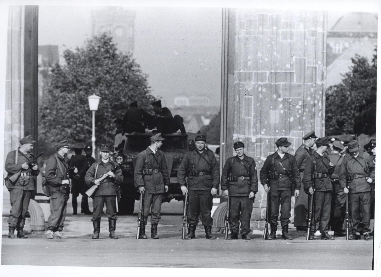 Members of the East Berlin Workers' Militia block the Brandenburg Gate while an armored car provides back up (August 1961) - Public Domain