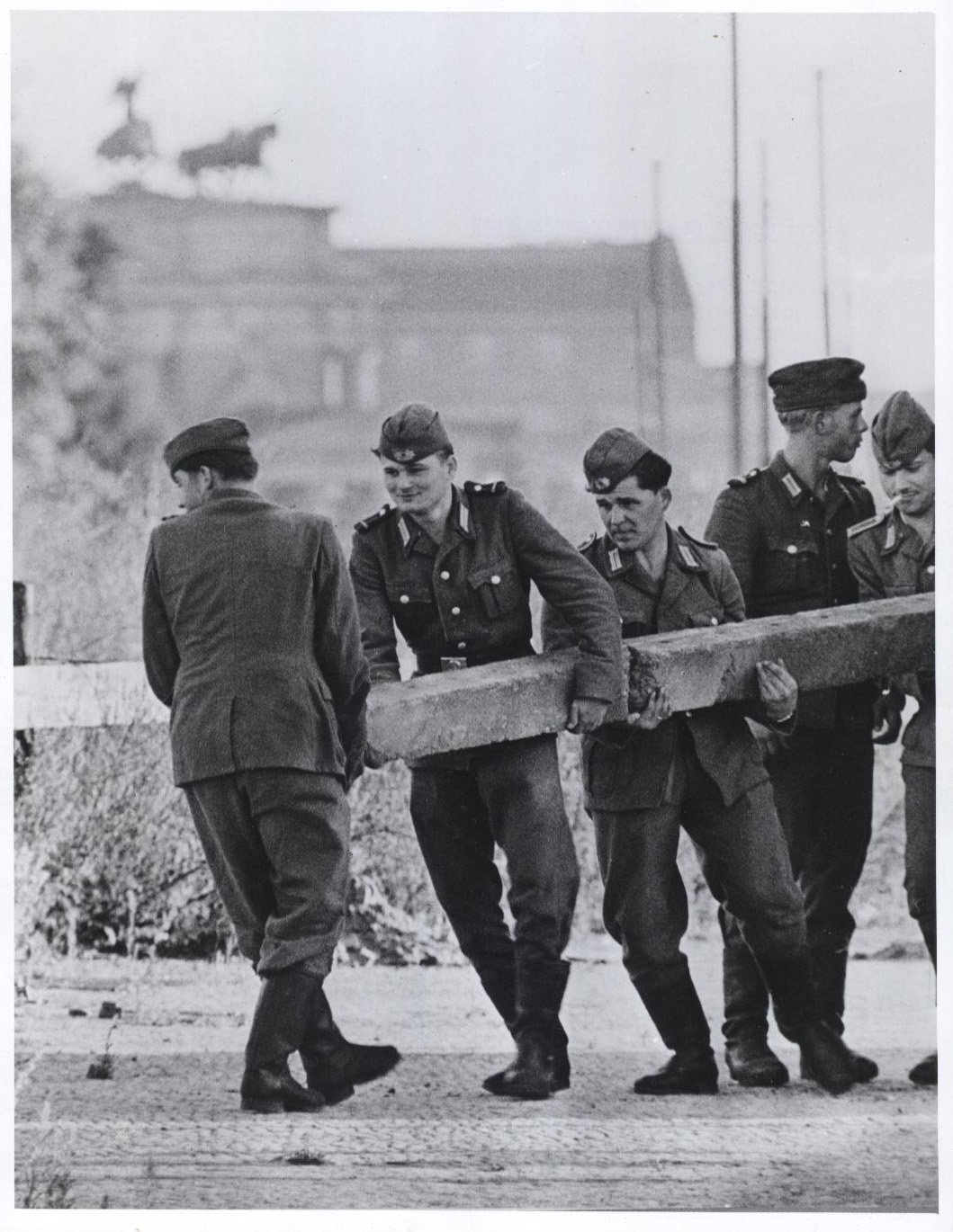 East German soldiers carry a post for the barbed wire fence being erected along the East and West Berlin border (August 1961) - Public Domain