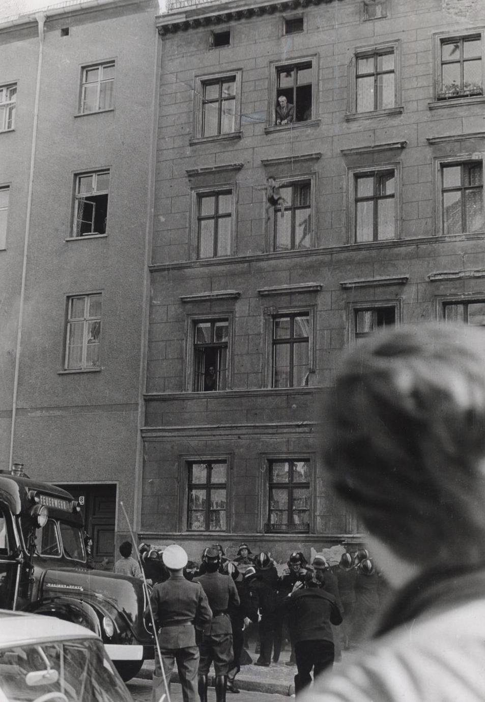 Four-year-old Michael Finder of East Germany is tossed by his father into a net held by residents across the border in West Berlin (October 1961) - Public Domain