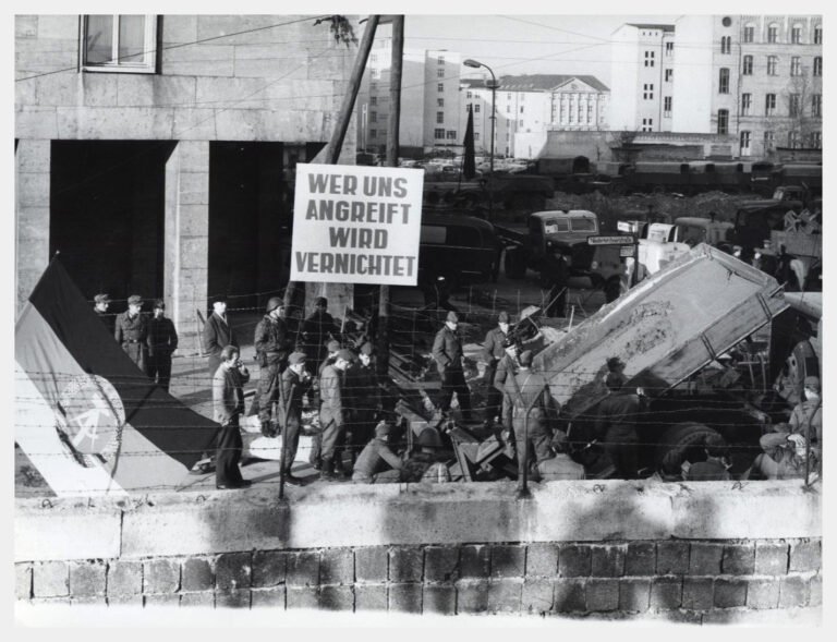 A sign at the Berlin Wall in East Berlin (November 1961) declares, “Whoever attacks us will be destroyed," - Public Domain