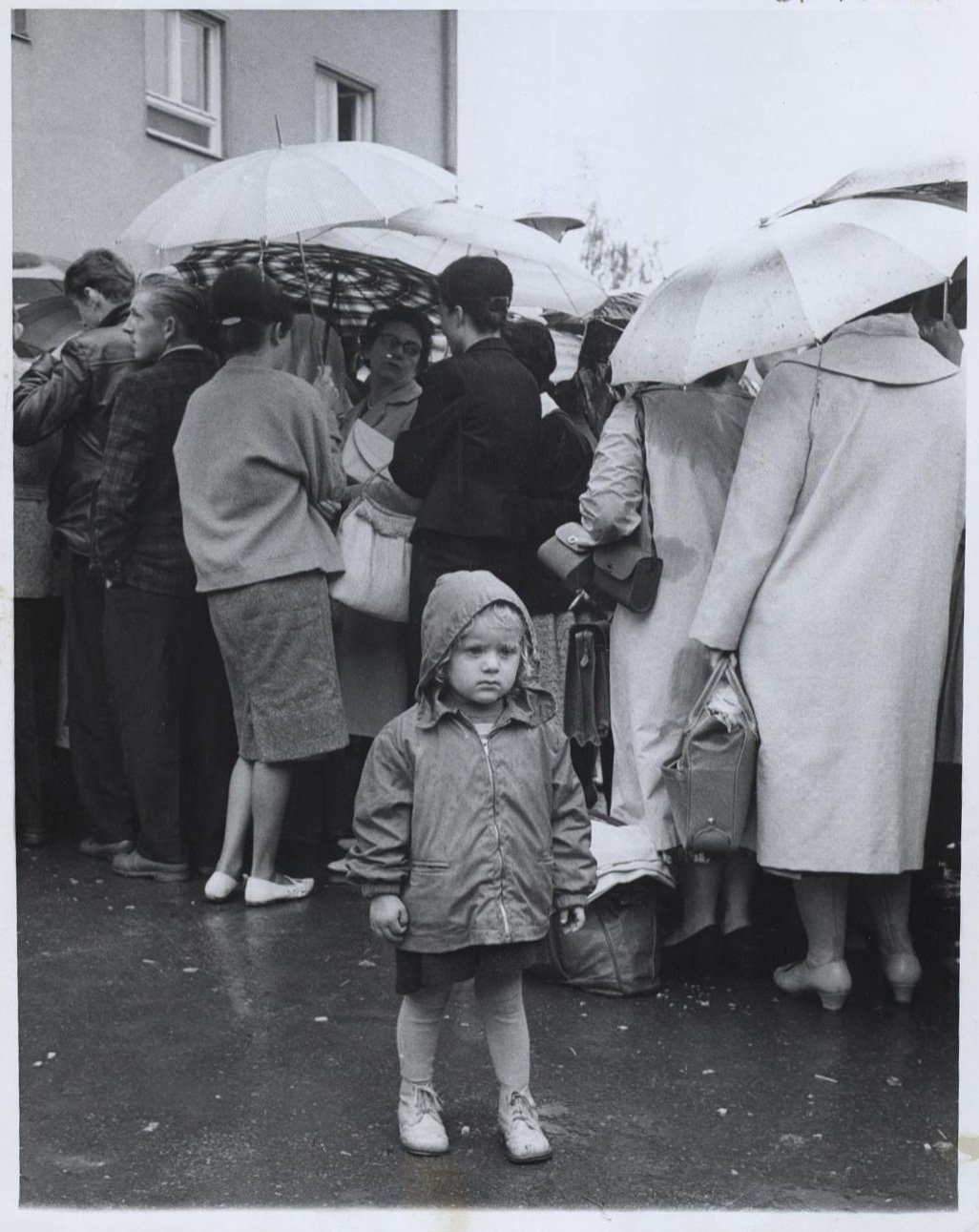A 3-year-old East German girl waits in the rain as her parents line up to register at a refugee center in West Berlin (1961) - CIA/Public Domain