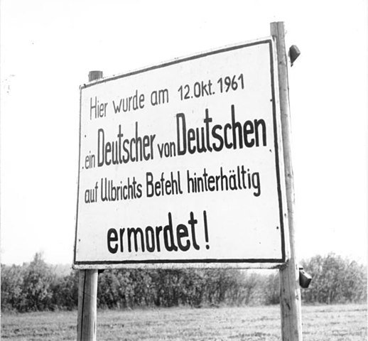 A sign on the Western side of the Iron Curtain (''Here on October 12th 1961 a German was murdered by a German on Walter Ulbricht's orders') - Public Domain