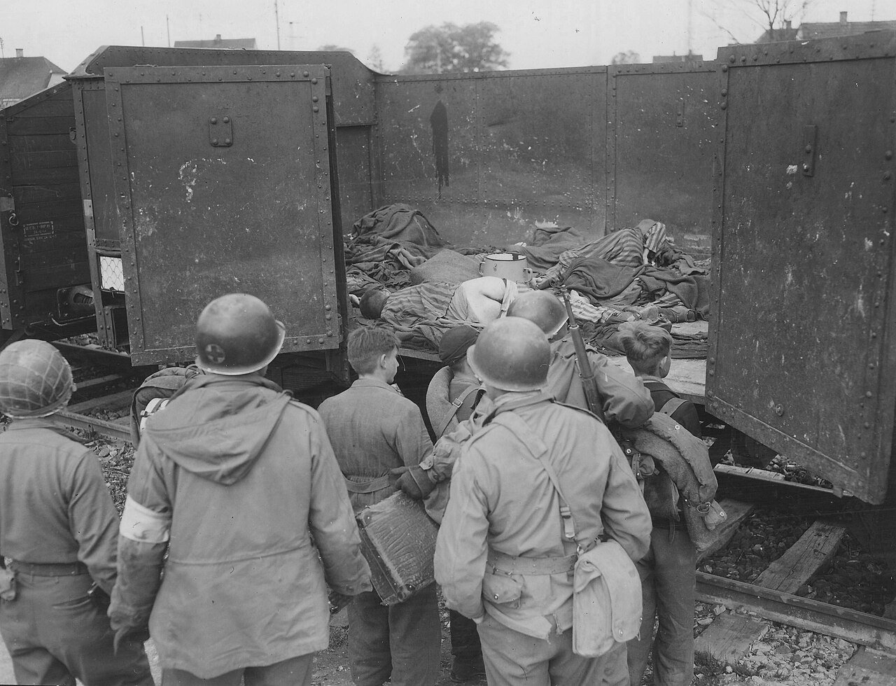 45th Infantry Division troops force suspected Hitler Youth members to view the bodies found in rail cars at Dachau Concentration Camp (1945) - Public Domain
