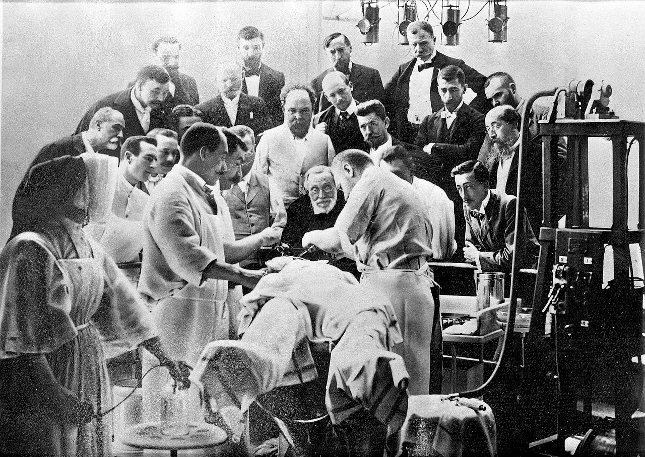 Rudolf Virchow (centre) observing an operation on a patient's skull - Public Domain