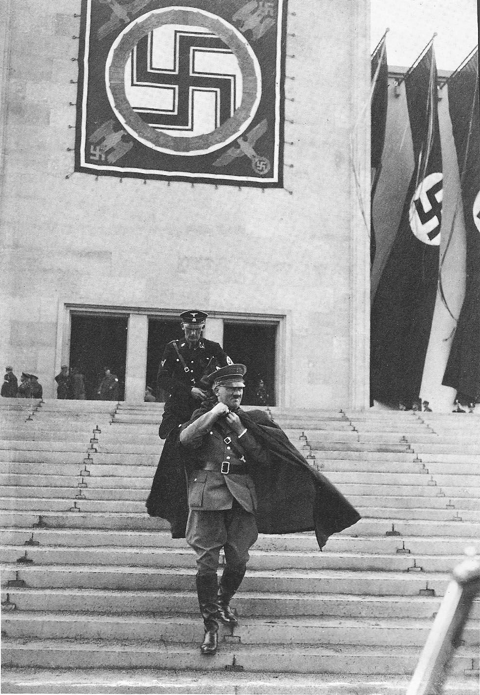 Adolf Hitler at the Nuremburg rally in 1936 with a Swastika flag behind him - Public Domain