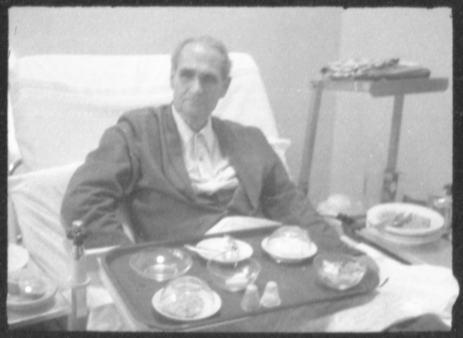 Clandestine photographs of Rudolf Hess sitting in his hospital bed with his tray of food in the Spandau Prison - United States Holocaust Museum