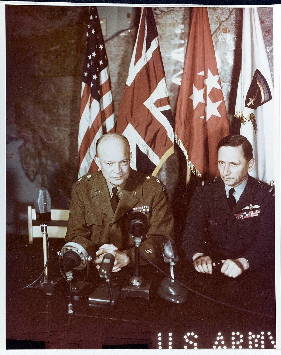 General of the Army Dwight D. Eisenhower, U.S. Army (left); and Air Chief Marshal Sir Arthur Tedder, Royal Air Force, address the World via motion picture and sound recordings, shortly after the German mission had signed the instrument of unconditional surrender, at Rheims, France (May 7th 1945) - Public Domain