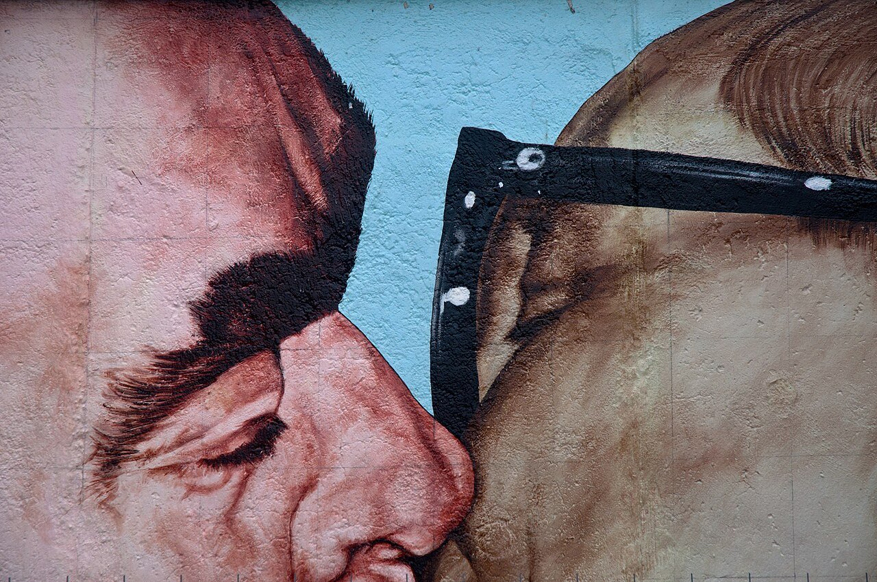 A close-up of the Socialist Kiss painted on the East Side Gallery - LeO Tiresias